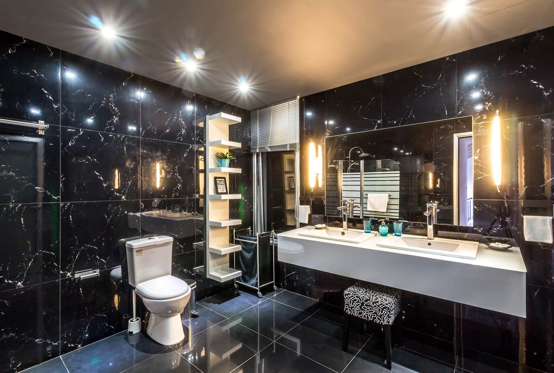bathroom with black reflective tiled walls and floating cabinets