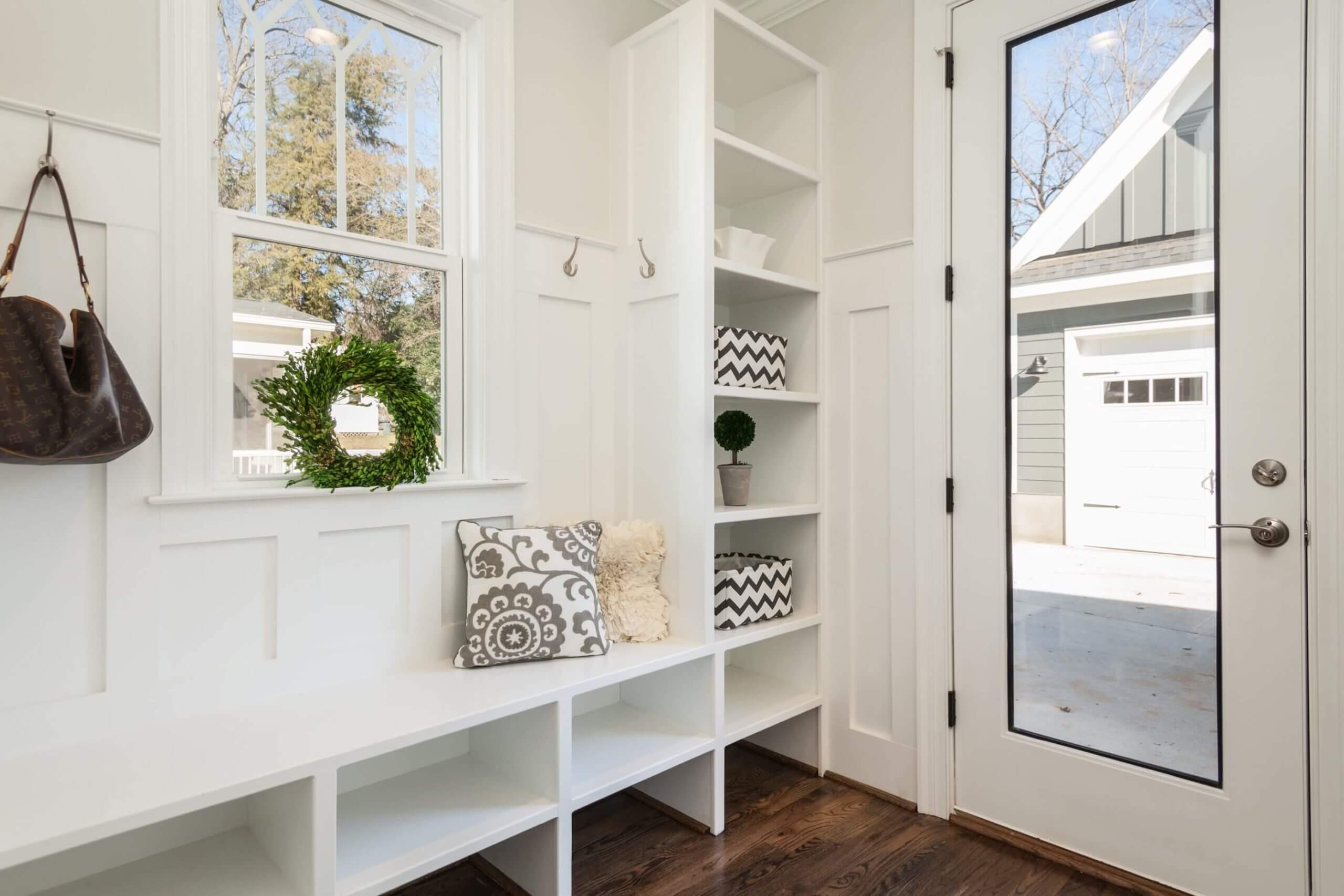 Mudroom with white interior, lots of shelving, and a glass pane door. 