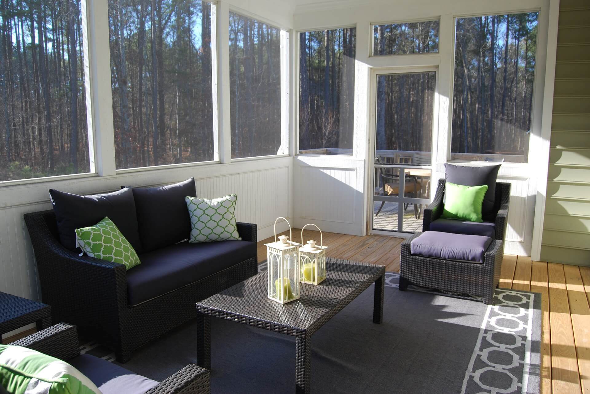 Sunroom with light wood floors, and dark furniture, surrounded by forest
