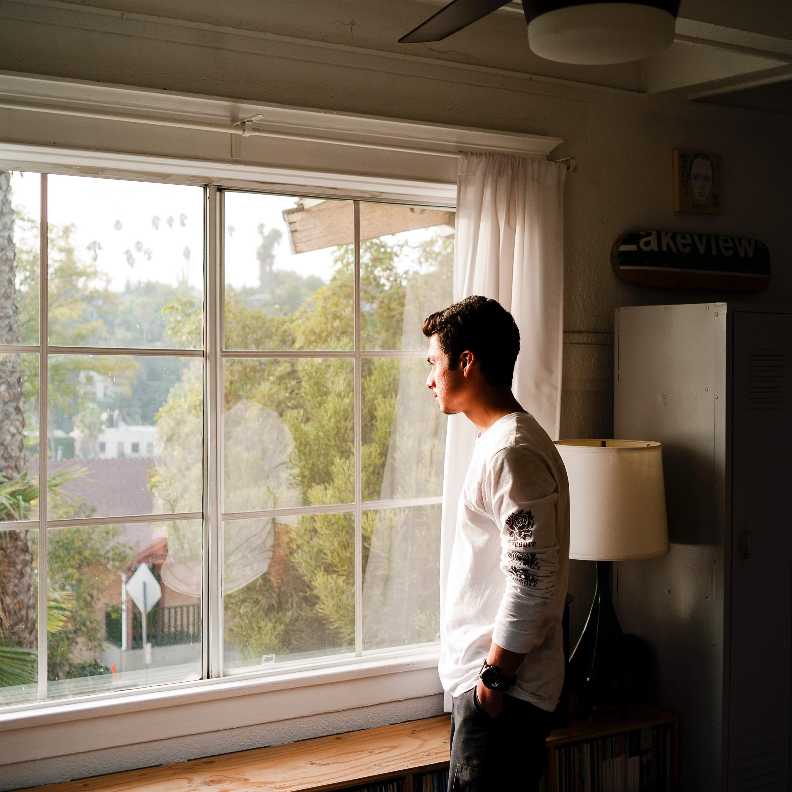 A man looking out of a set of windows.